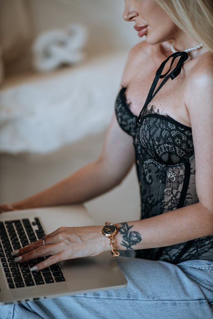 Stylish woman in lace corset working on a laptop indoors.