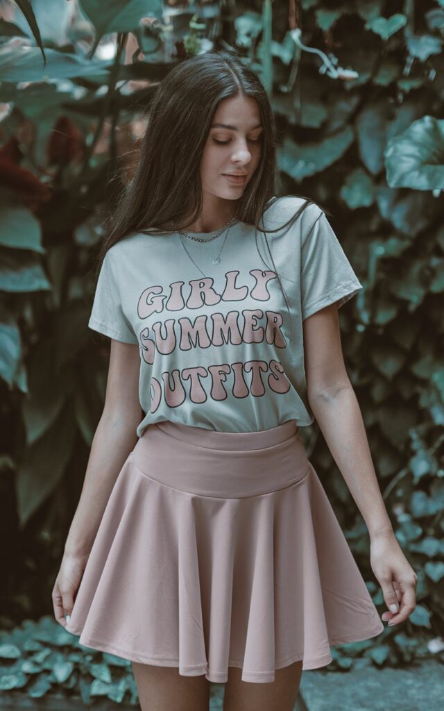 A natural-looking young woman wearing a feminine graphic tee paired with a flared skirt. Theme girly summer outfits