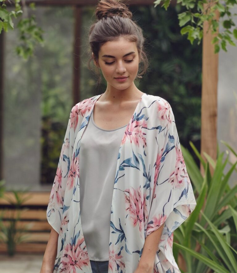 A natural-looking young woman wearing a flowy kimono layered over a simple tank and shorts. Theme cute summer outfits