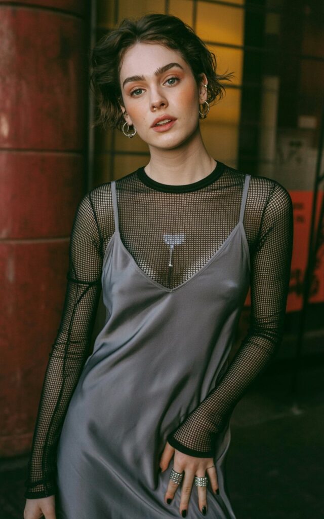 A natural-looking young woman wearing a mesh top layered under a slip dress. Theme emo outfits