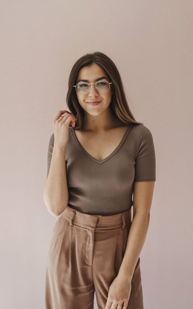 A natural-looking young woman wearing a v-neck top styled with tailored pants. Theme fashion inspo outfits