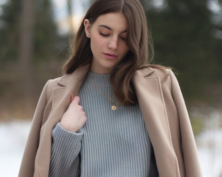 A natural-looking young woman wearing baggy jeans styled with a structured wool coat layered over a simple knit sweater. Theme baggy jeans outfit winter