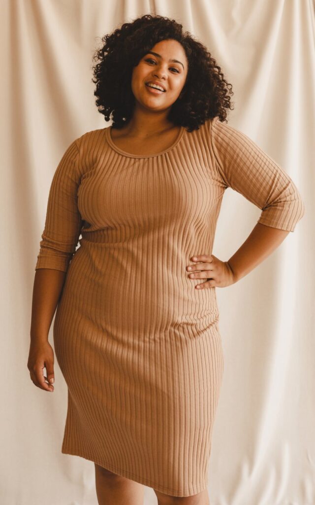 "A natural-looking young curvy woman wearing a body-hugging ribbed midi dress. Theme: curvy outfits."