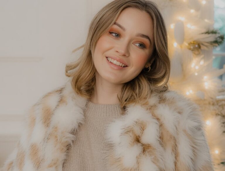 A natural-looking young woman wearing a faux fur jacket over a neutral outfit. Theme christmas party outfits