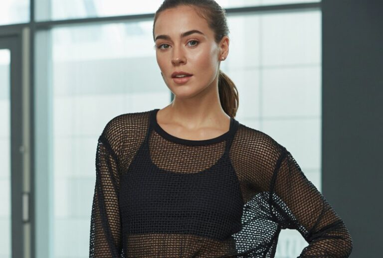 A natural-looking young woman wearing a mesh sleeve top with solid capris. Theme gym outfits for women