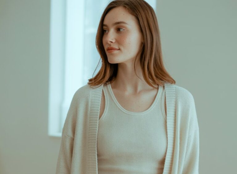 A natural-looking young woman wearing an oversized knit sweater paired with tailored trousers and ankle boots. Theme winter outfits aesthetic