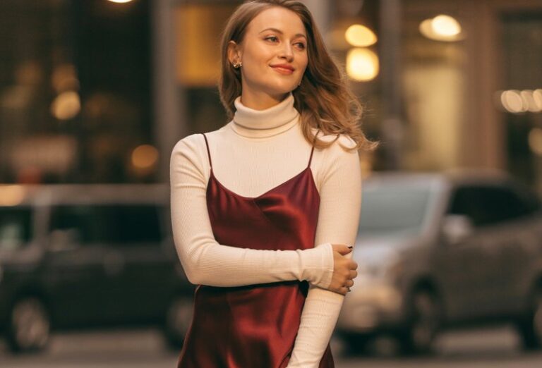 A natural-looking young woman wearing a monochrome winter white outfit with mixed textures and nude accessories. Theme date night outfit winter