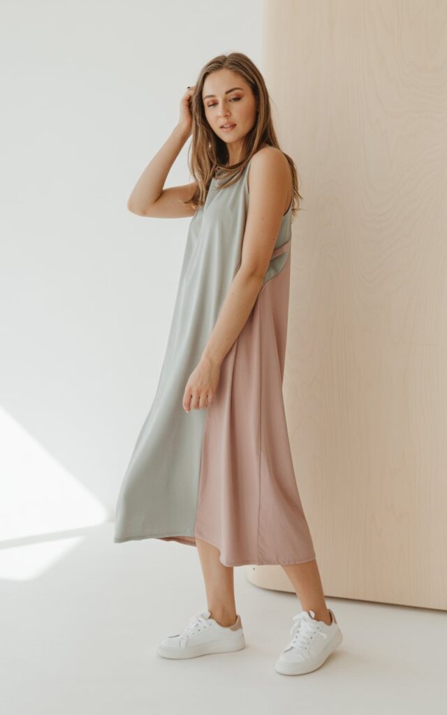 A natural-looking young woman wearing a flowy midi dress paired with clean white sneakers. Theme lookbook outfits